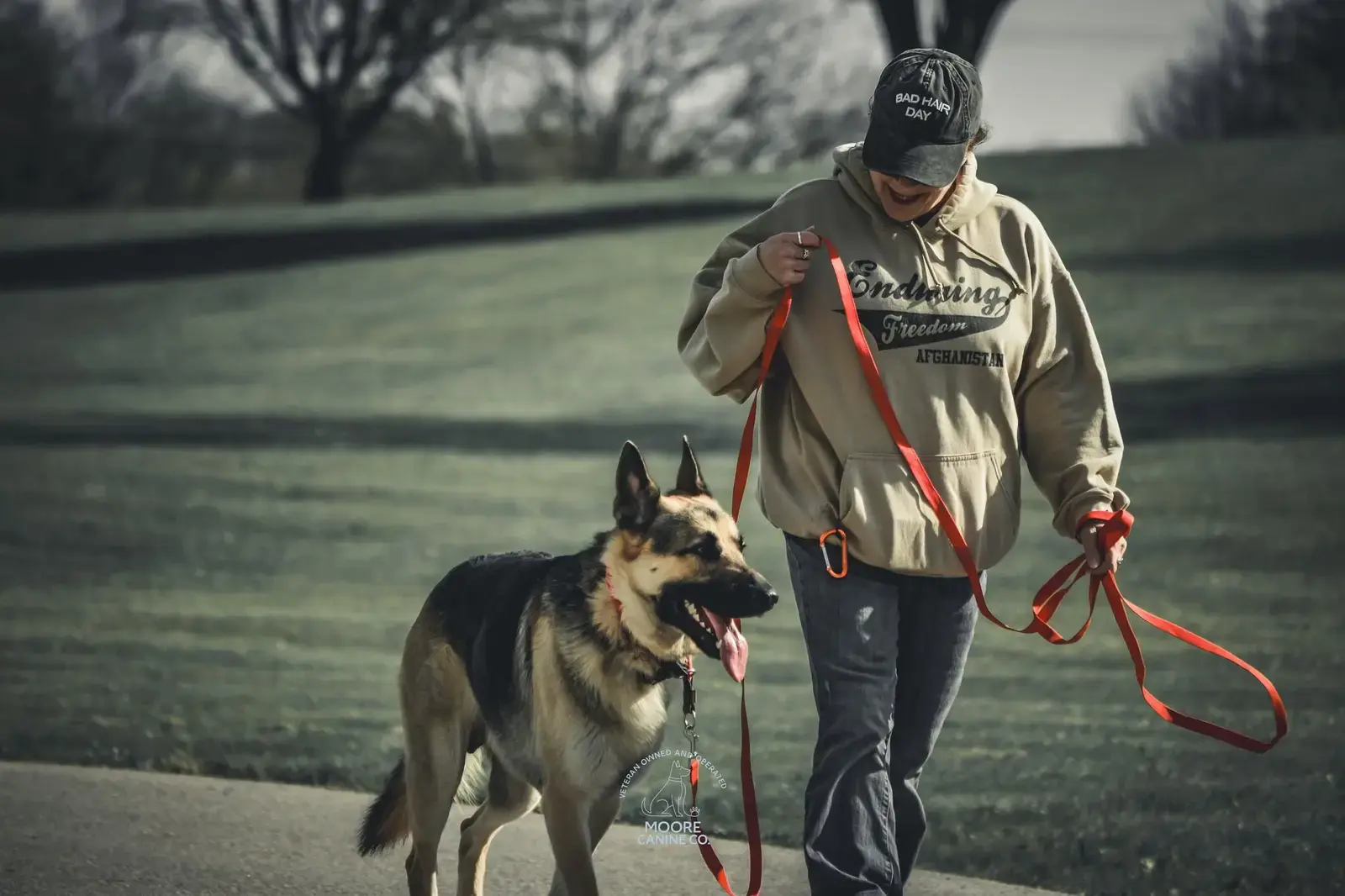 A happy client walking her grinning German Shepherd on a loose leash